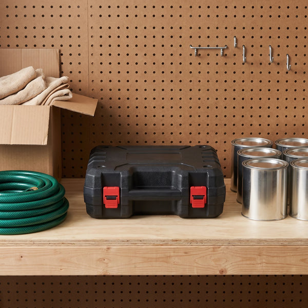 A tidy garage shelf with a rigid black hard case with two red latches closed at the centre, a coiled green garden hose and a box of plain cloths at the left, paint tins at the right and a pegboard behind